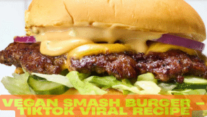 Close-up of a crispy vegan smash burger with melted vegan cheese, onions, and sauce dripping inside a toasted brioche bun.